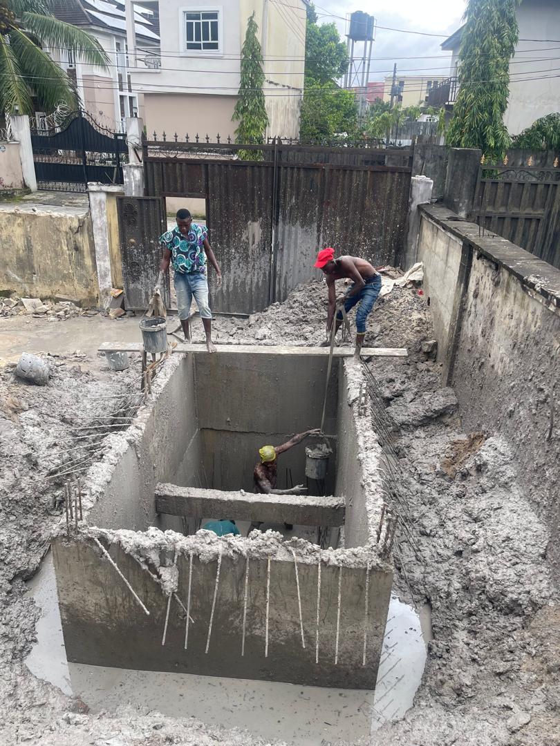 Concrete drainage and civil-works construction beside a site perimeter.