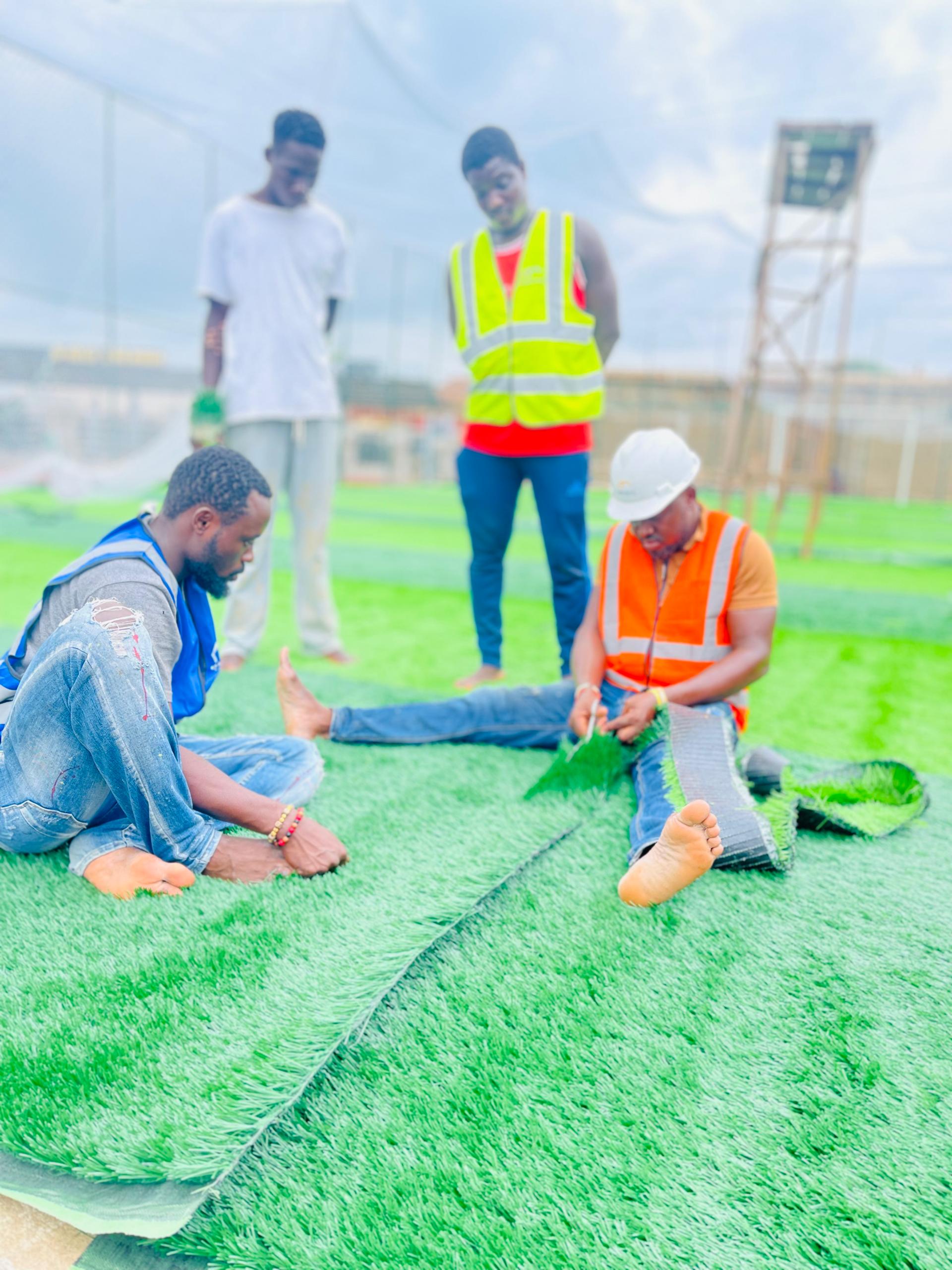 Crew installing synthetic sports turf on a prepared playing surface.